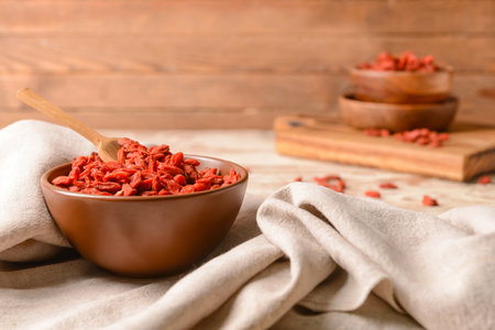 Bowl with dried goji berries on light wooden backgroundの写真素材