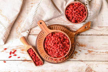 Bowl and scoop with dried goji berries on light wooden backgroundの写真素材