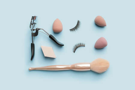 Makeup sponges with brush and eyelash curler on color background