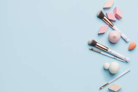 Makeup sponges with brushes on color background