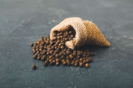 Bag with peppercorns on dark background