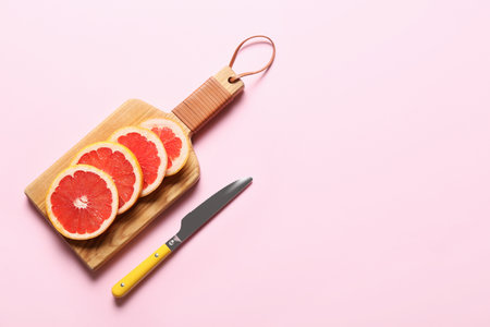 Board with slices of ripe grapefruit and knife on color backgroundの写真素材
