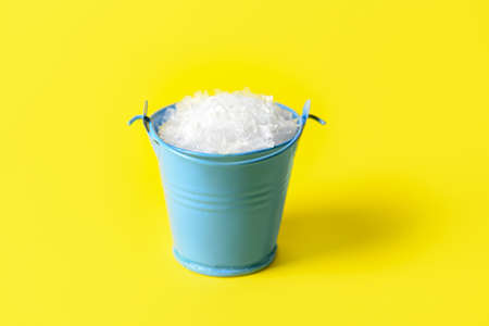 Metal bucket with snow on color backgroundの写真素材