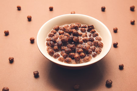 Bowl with chocolate corn balls and milk on color backgroundの写真素材