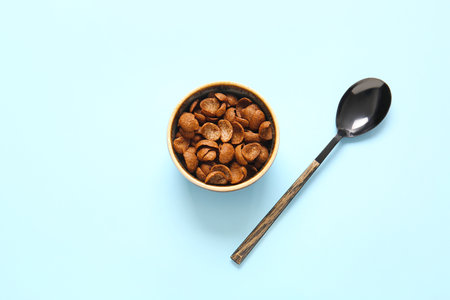 Bowl with chocolate corn flakes and spoon on color backgroundの写真素材