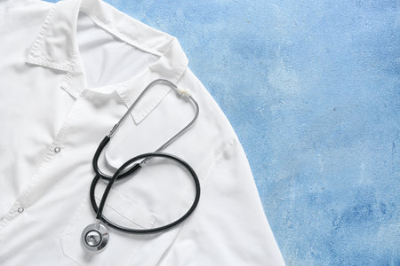 Modern stethoscope and doctor's uniform on color backgroundの写真素材