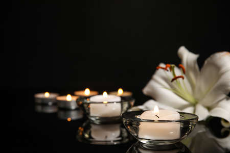 Burning candles and lily flower on dark backgroundの写真素材