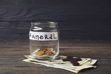 Jar with money and cross on dark wooden background