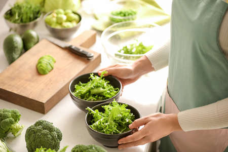 Woman with bowls of fresh salad on light tableの写真素材