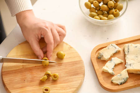 Woman cutting olives on light backgroundの写真素材