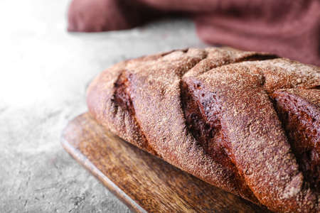 Board with fresh bread on gray background