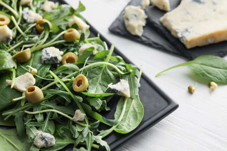 Plate of tasty salad with olives on light wooden backgroundの写真素材
