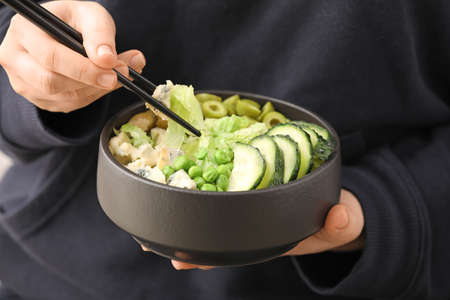 Woman eating tasty salad with fresh vegetables, closeup