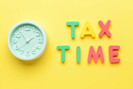 Alarm clock with text TAX TIME on color backgroundの写真素材