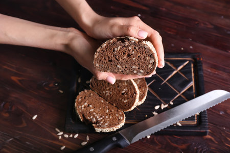 Woman with fresh cut bread on wooden background