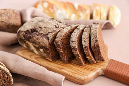 Board with fresh cut bread on color background