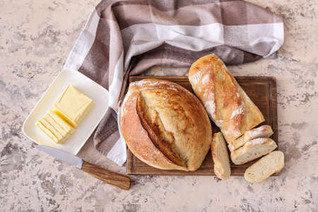 Board with fresh cut bread on grunge background