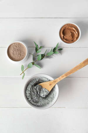 Bowls with cosmetic clay on light wooden backgroundの写真素材