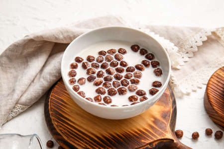 Bowl with chocolate corn balls and milk on light backgroundの写真素材