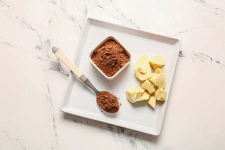 Bowl and spoon with cocoa powder and butter on light backgroundの写真素材