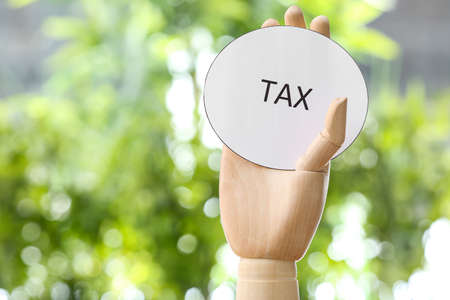 Paper with word TAX and wooden hand outdoorsの写真素材
