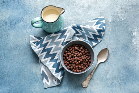 Bowl with chocolate corn balls and jug of milk on color backgroundの写真素材