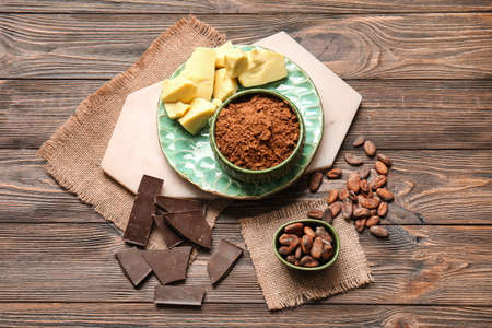 Composition with cocoa powder, beans, butter and chocolate on wooden backgroundの写真素材