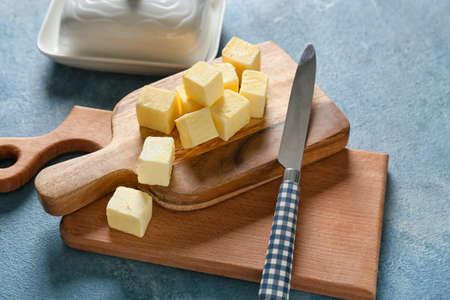 Wooden boards with fresh butter and knife on color backgroundの写真素材