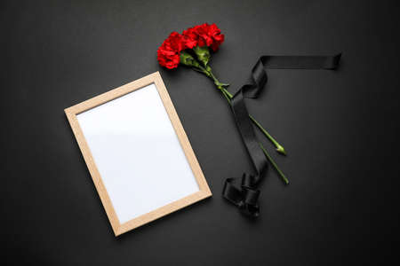Carnation flowers with black ribbon and photo frame on dark backgroundの写真素材
