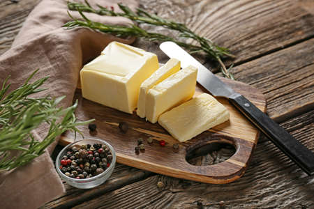 Board with fresh butter and knife on wooden backgroundの写真素材