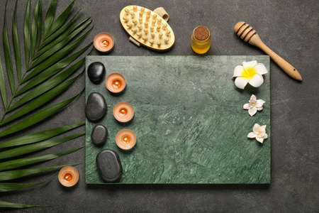 Beautiful spa composition with burning candles and palm leaf on dark backgroundの写真素材