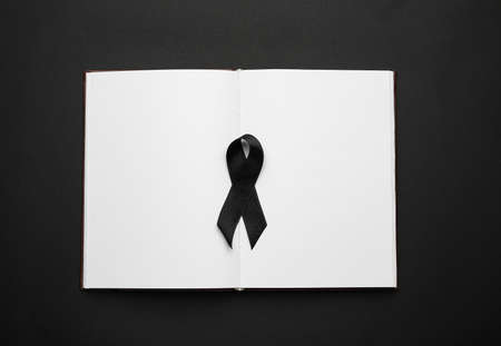 Black funeral ribbon with book on dark background