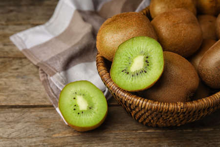 Wicker basket with tasty kiwi on wooden backgroundの写真素材