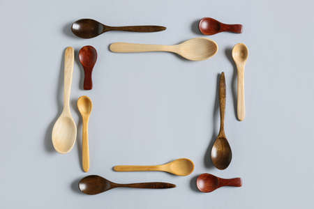 Frame made of wooden spoons on light background