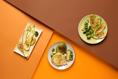 Plates with tasty grilled vegetables on color background