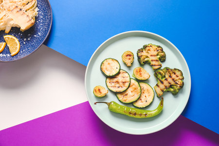 Plates with tasty grilled vegetables on color backgroundの写真素材