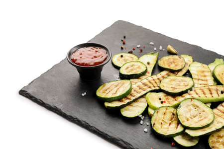 Board with tasty grilled squashes on white backgroundの写真素材