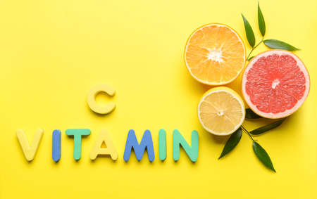 Text VITAMIN C and citrus fruits on color background