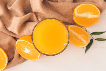 Glass with tasty orange juice on light wooden background