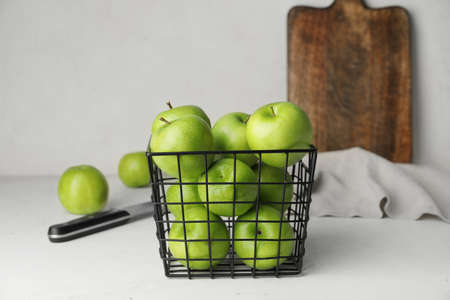 Basket with fresh green apples on tableの写真素材