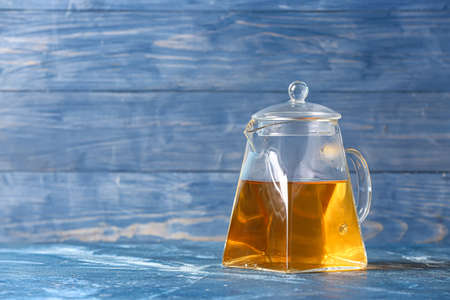 Teapot with hot tea on color wooden backgroundの写真素材