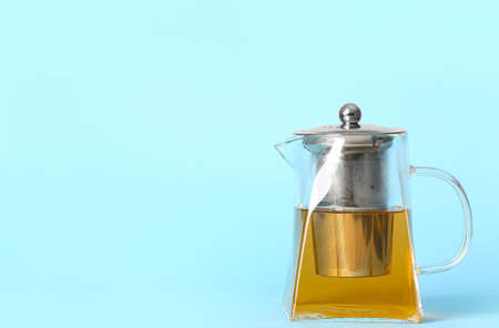 Teapot with hot tea on color backgroundの写真素材