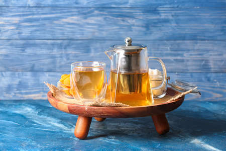 Teapot with hot tea and glass on color backgroundの写真素材