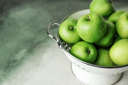 Colander with fresh green apples on color backgroundの写真素材