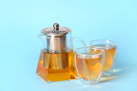 Teapot with hot tea and glasses on color backgroundの写真素材