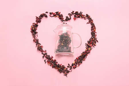 Composition with teapot and heart made of dry leaves on color backgroundの写真素材