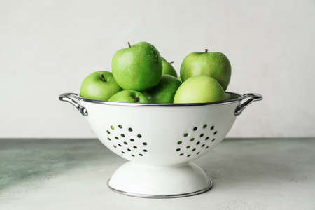 Colander with fresh green apples on light backgroundの写真素材