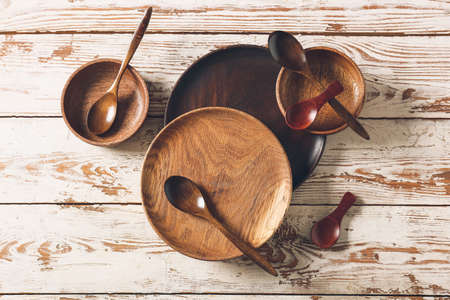 Spoons, bowls and plates on light wooden backgroundの写真素材