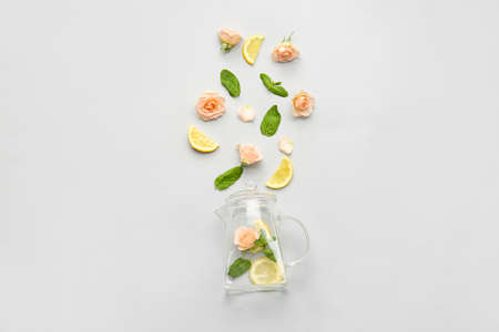 Composition with teapot, lemon, rose flowers and mint on light backgroundの写真素材