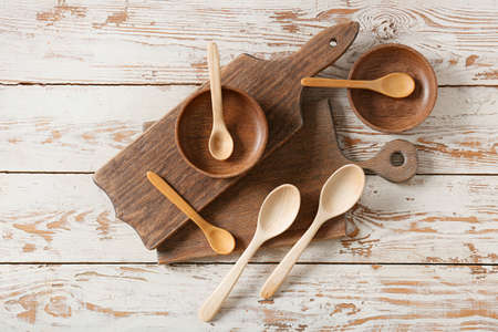 Spoons, bowls and chopping boards on light wooden backgroundの写真素材